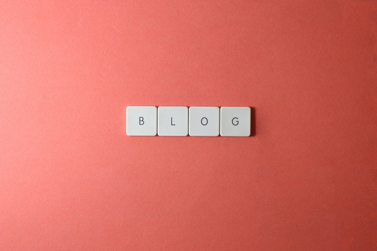 A minimalist image of keyboard keys spelling BLOG on a coral background.